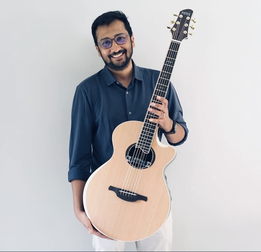 Murthy holding an acoustic guitar